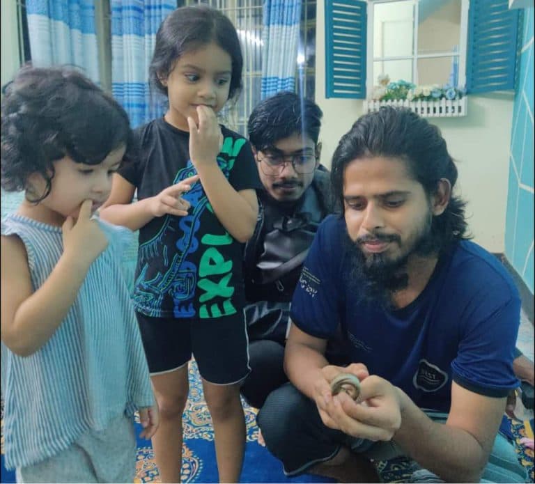 A 3SA rescuer gently showing a small snake to two curious children at home