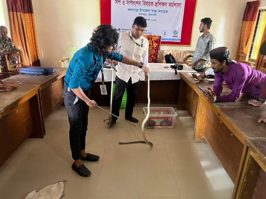 A 3SA trainer demonstrating safe snake handling with tongs during a workshop